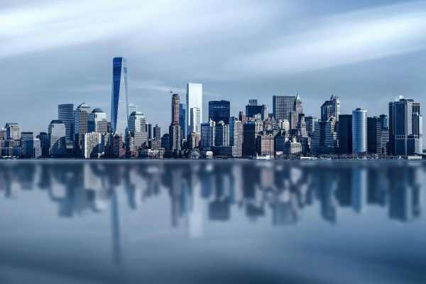 Stunning New York City skyline with modern skyscrapers reflecting on a calm river.